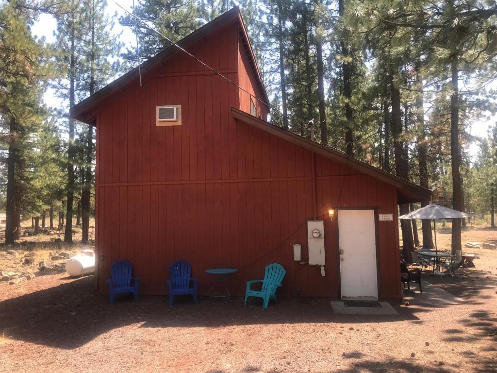 苏珊维尔Cheerful 2-Bedroom Cottage Near Eagle Lake的前面的红色谷仓,有蓝色的椅子