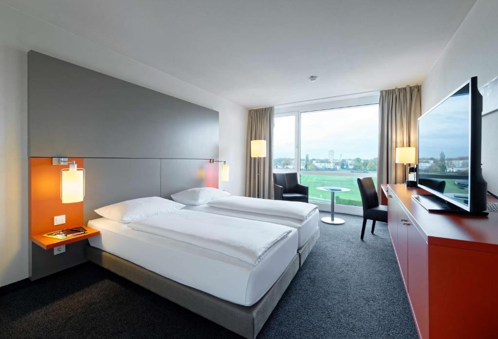 不莱梅赛马场大西洋饭店的酒店客房配有一张床、一张书桌和一台电视。