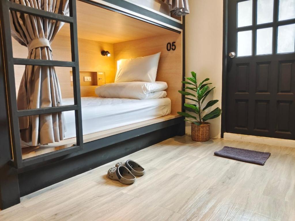 合艾Hope Hostel Hatyai的一间卧室配有一张带镜子和一双鞋的床