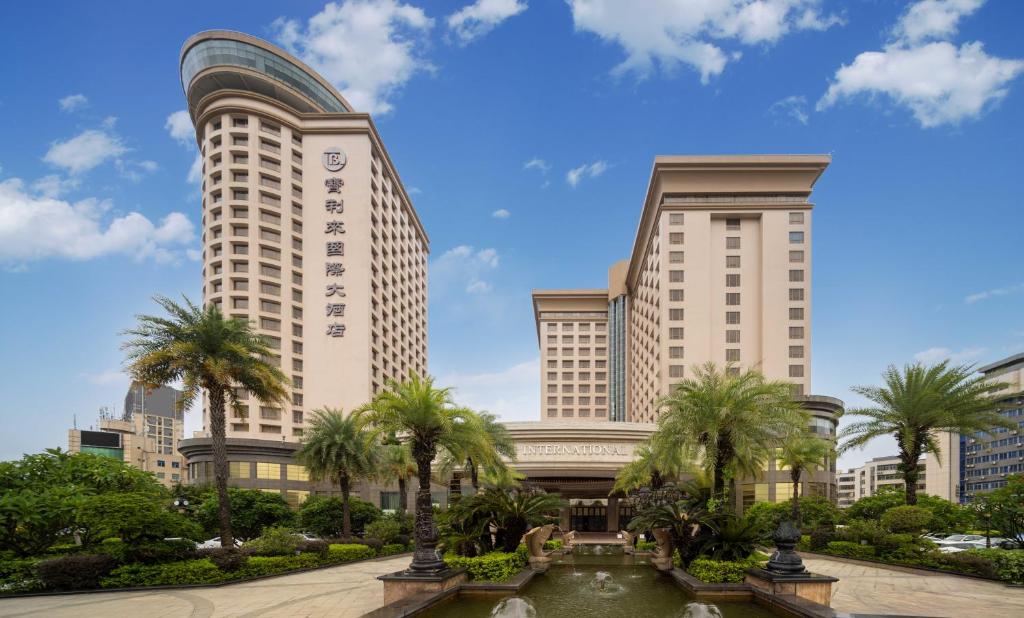 宝安深圳宝利来国际大酒店(宝安,福永)的两座高大的建筑,在喷泉前有棕榈树