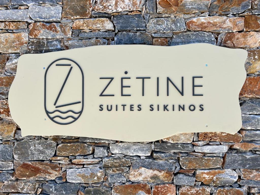 锡基诺斯岛ZETINE SUITES SIKINOs的砖墙上的标志,上面写着“zine suites”的 ⁇ 声