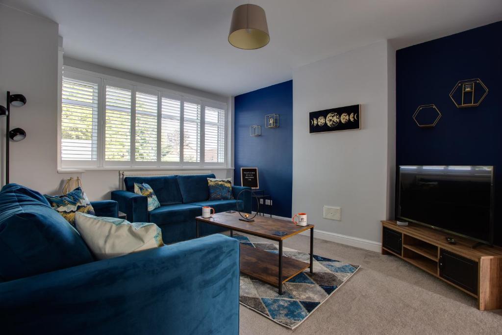 Sunbury CommonSAXON ROAD - A 3 Bedroom House with Garden by Prestigious Stays - Includes Wifi, Netflix & Amazon Alexa的客厅配有蓝色的家具和电视