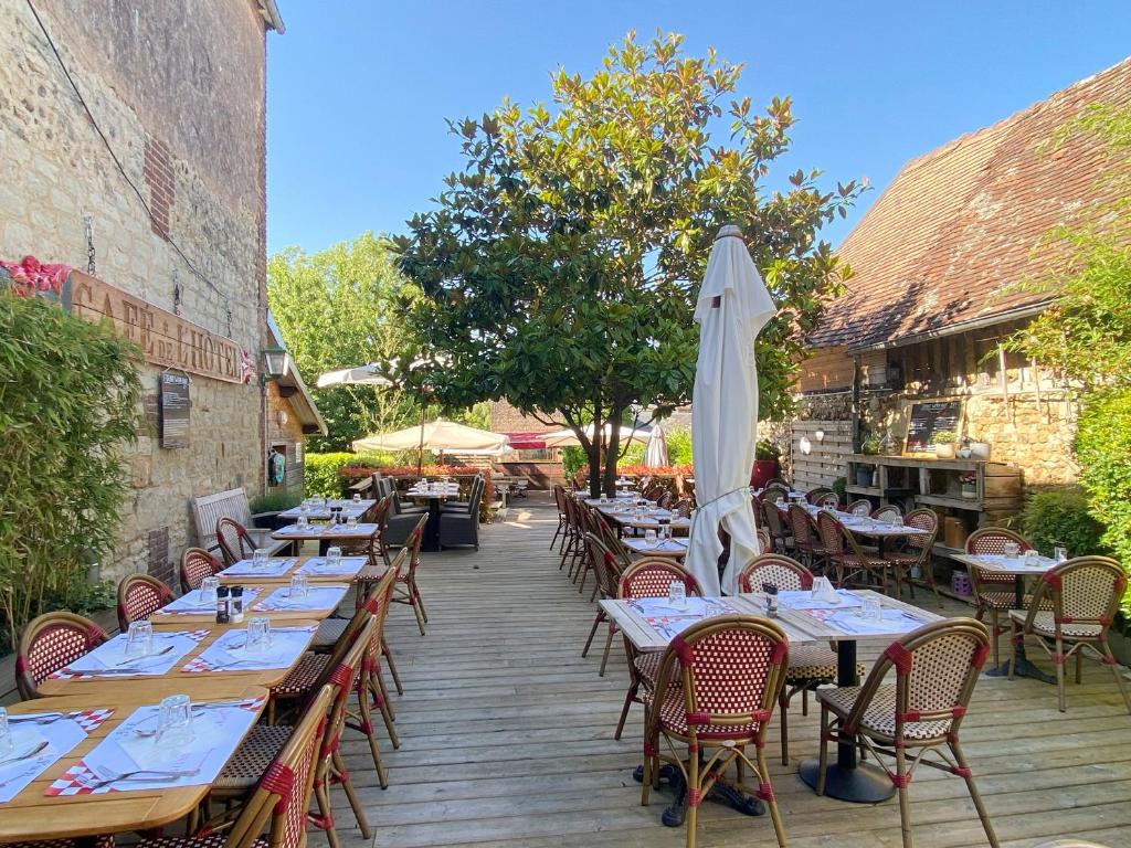 Beaumont-en-Auge普蒂特比尤蒙特酒店的室外餐厅设有桌子和遮阳伞