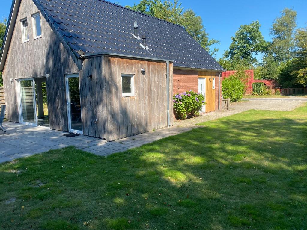 GasselteVakantiehuisje drenthe gasselterveld的一座房子旁边的谷仓,有草地庭院