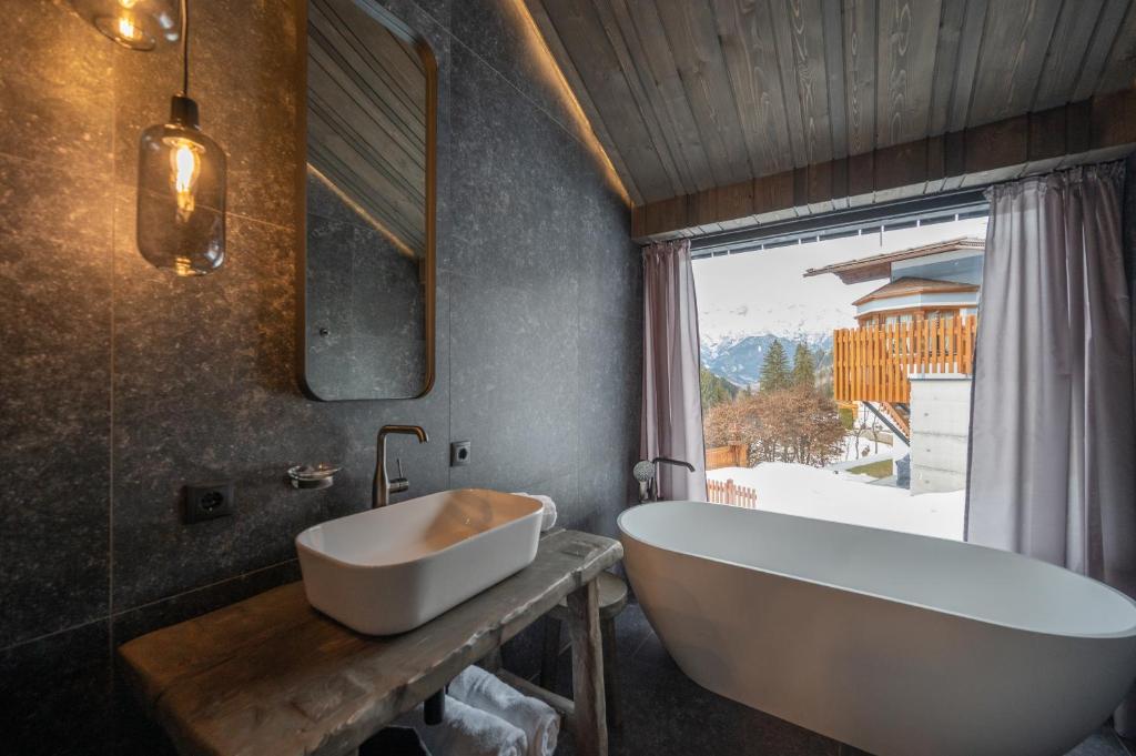卡普尔Paznauner Villen - Villa II的带浴缸、水槽和窗户的浴室