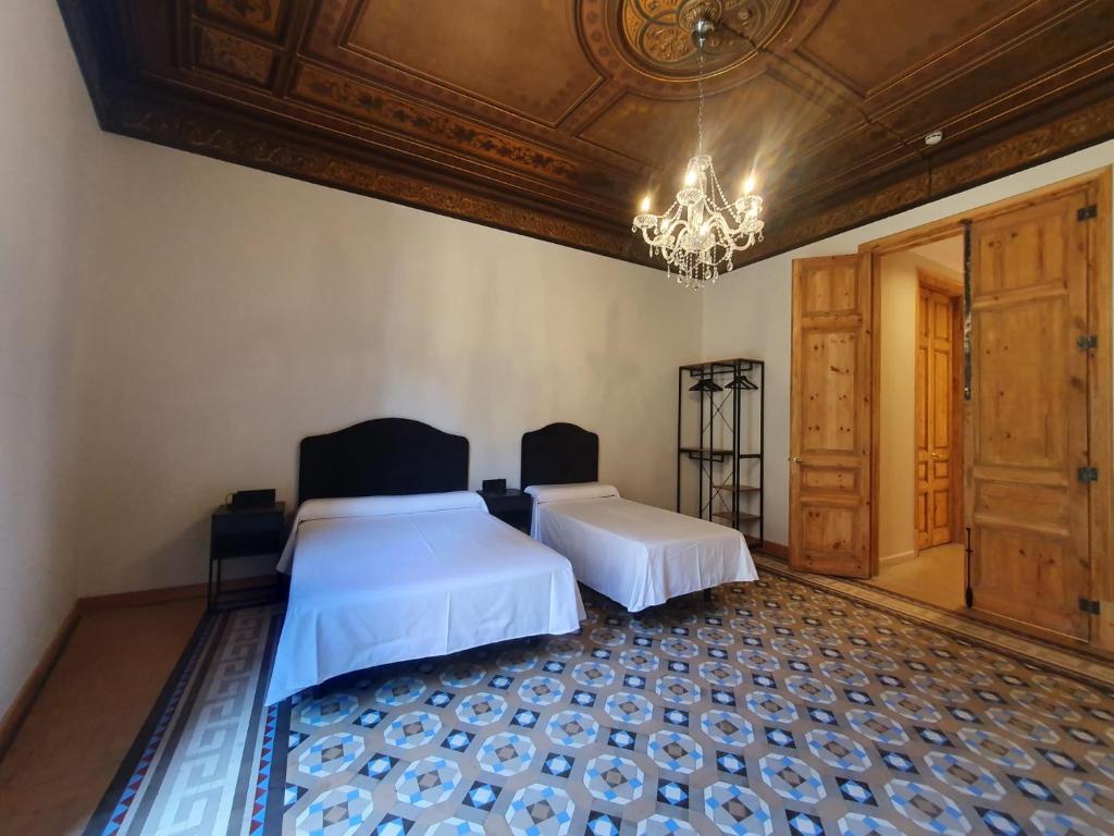 巴塞罗那洛桑酒店的一间卧室配有两张床和吊灯。