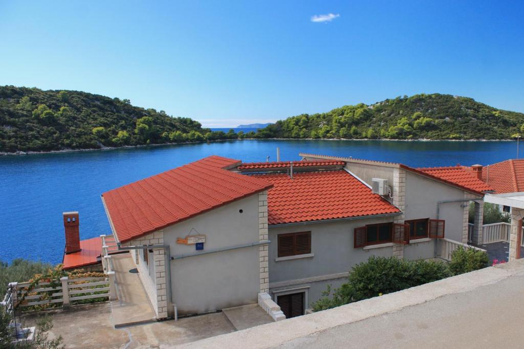 普利兹巴Apartments by the sea Karbuni, Korcula - 9308的水体旁有红色屋顶的建筑