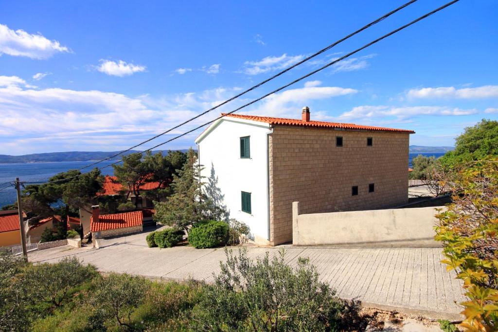 麦米科Apartments by the sea Marusici, Omis - 10012的一座白色的小建筑,有红色的屋顶