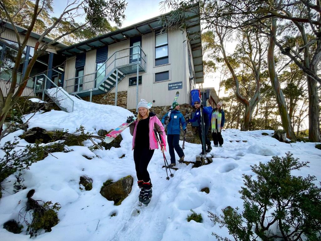 Baw Baw VillageTanjil Creek Lodge的一位在房子前行走在雪中的女人