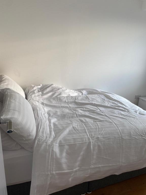 克罗伊登Morden 1 bedroom City- Apt Central stylish living的一张未铺好的床,上面有白色床单