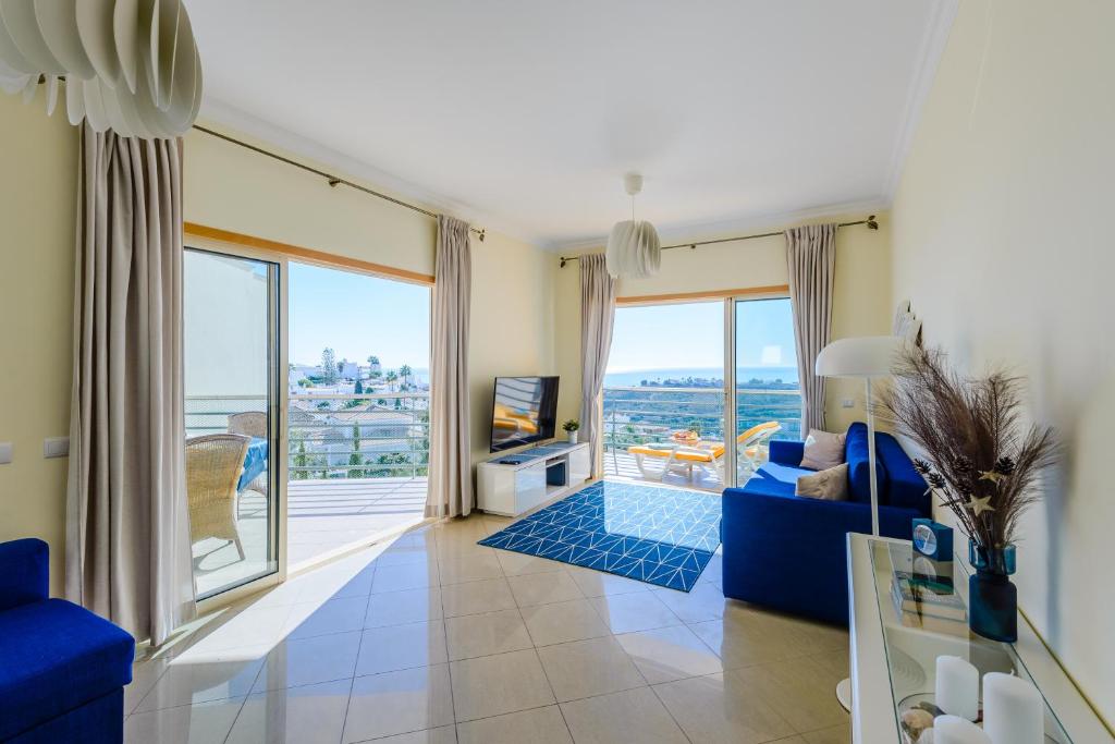 阿尔布费拉Ocean view Apartment with 3 spacious Terraces, 2 Swimming pools & Tennis court的客厅设有蓝色的沙发和大窗户