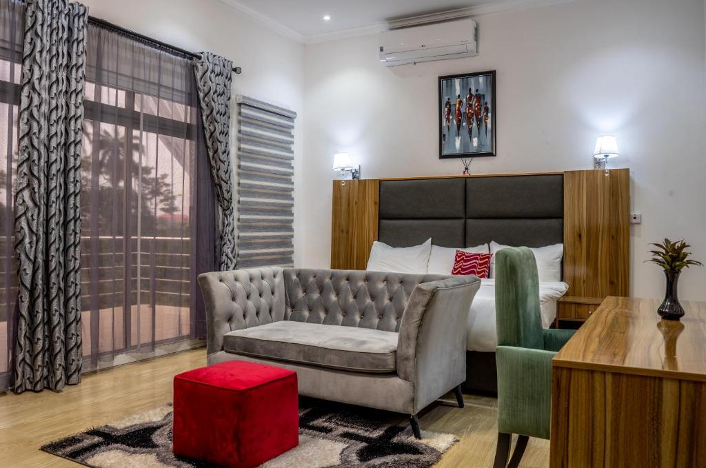 OkpanamNelson Mandela Gardens的一间卧室配有一张床、一张沙发和一把椅子