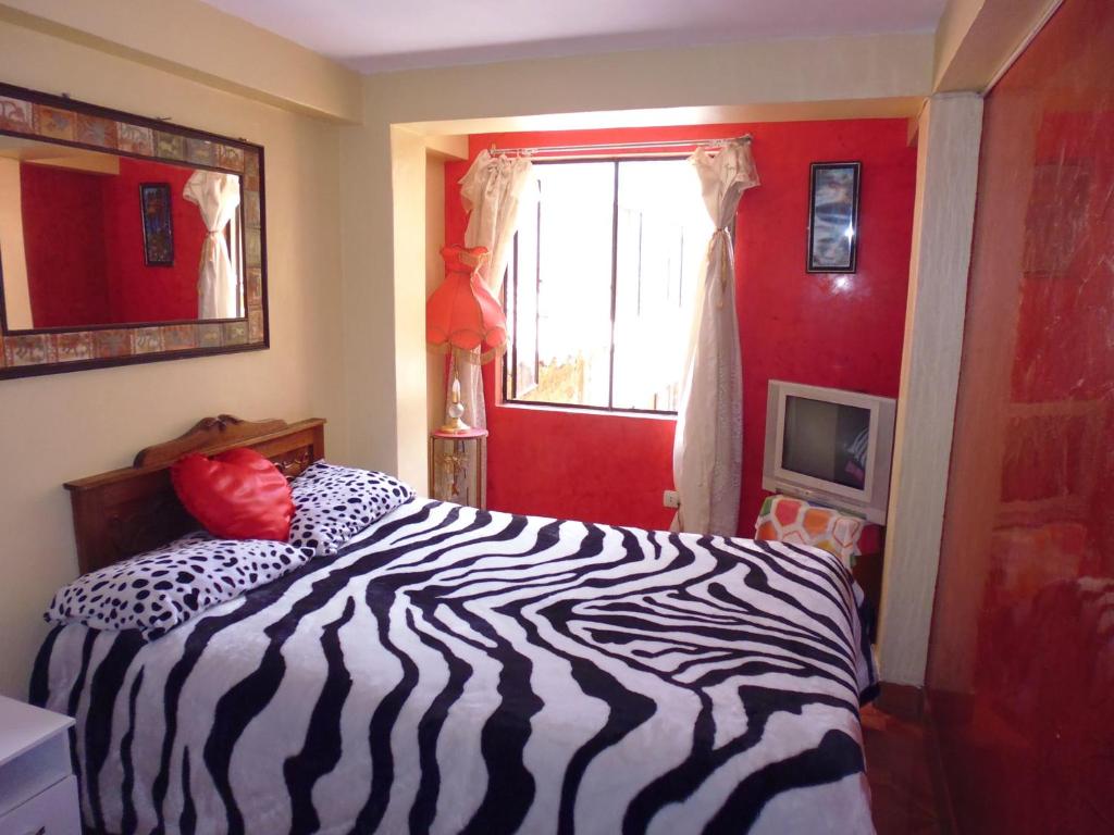 库斯科Hospedaje Pumacurco Betty的卧室里一张斑马印花床,卧室里设有红色的墙壁