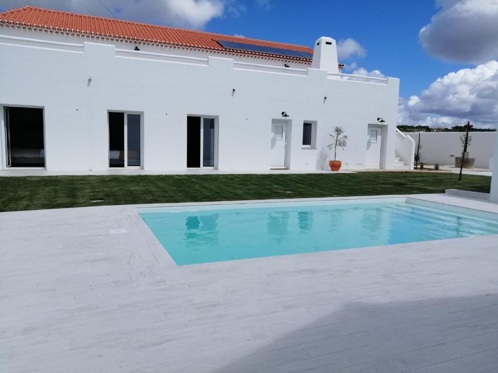 CarvalhalPé no Campo Suites and Villa的白色房子前的游泳池