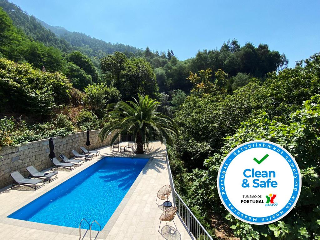 吉尔斯Chalet Villas Gerês的游泳池配有椅子和标志,干净而安全