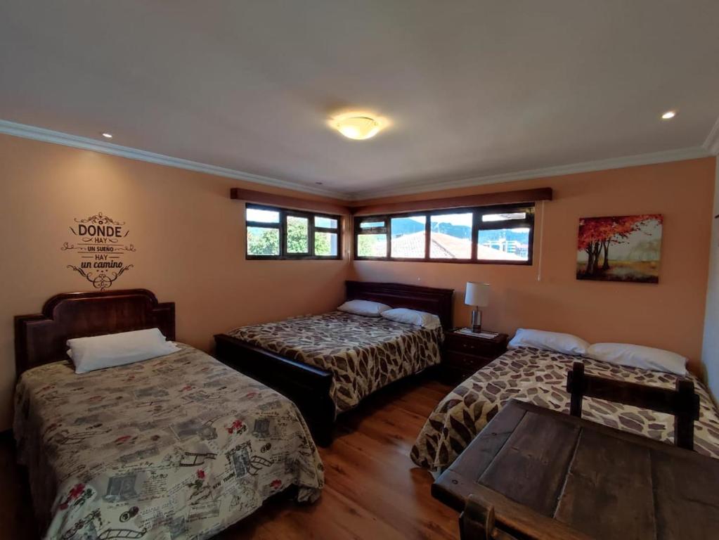 昆卡Casatodosantos的客房设有两张床、一张桌子和窗户。