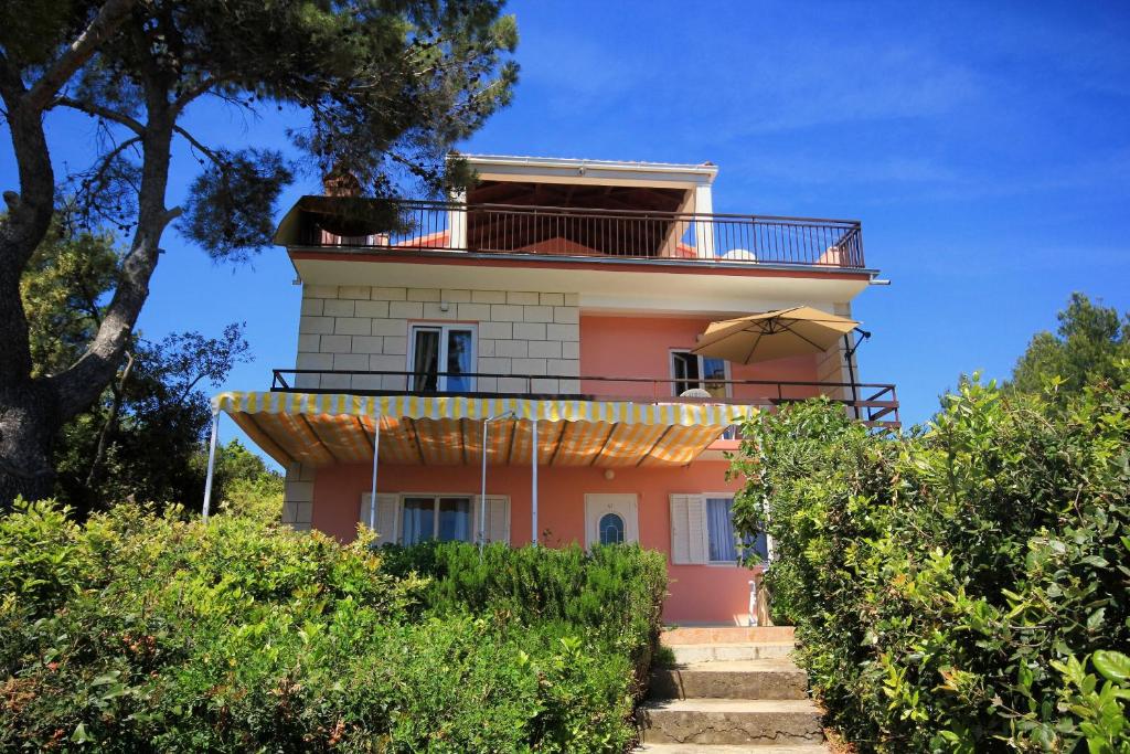 普利兹巴Family friendly seaside apartments Prizba, Korcula - 10061的粉红色的房子,设有阳台和雨伞