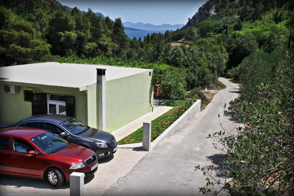 特雷斯塔尼克Holiday house with a parking space Trstenik, Peljesac - 10195的两辆汽车停在山丘上一座建筑旁边