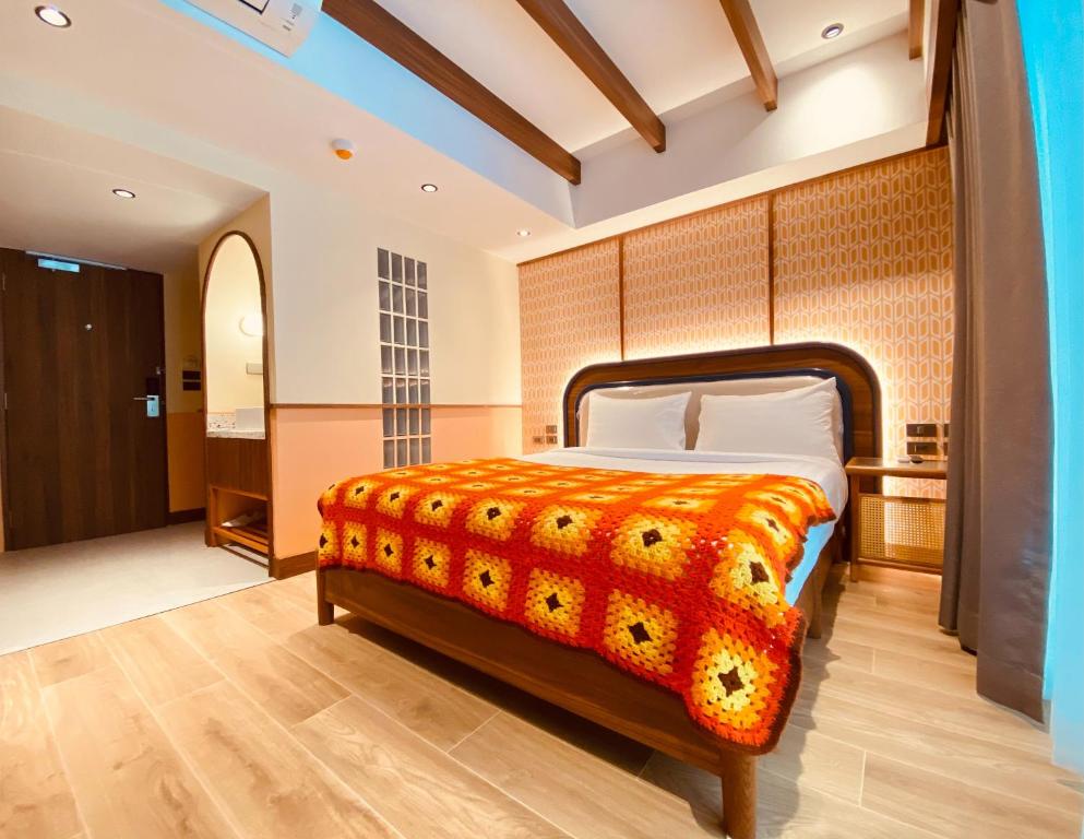 曼谷Miami Hotel Bangkok - SHA Plus的一间卧室配有一张带橙色毯子的床