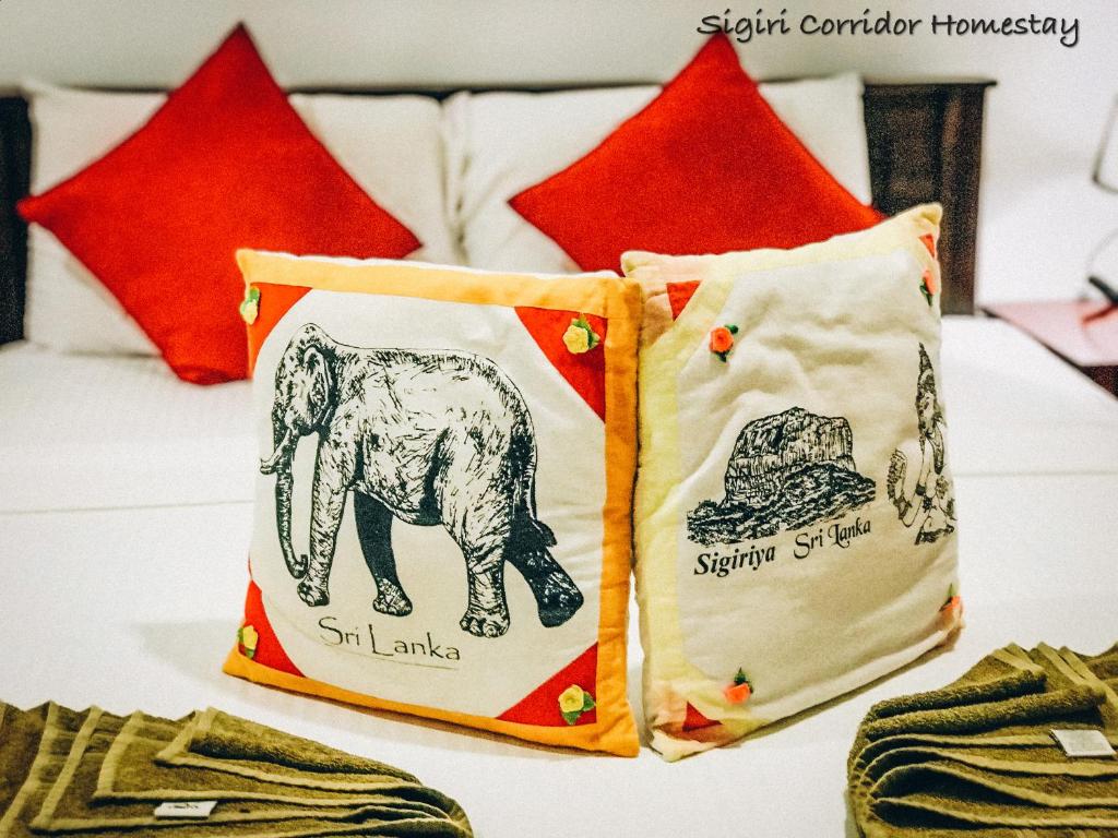 锡吉里亚Sigiri Corridor Home Stay的床上的2个枕头和红色枕头