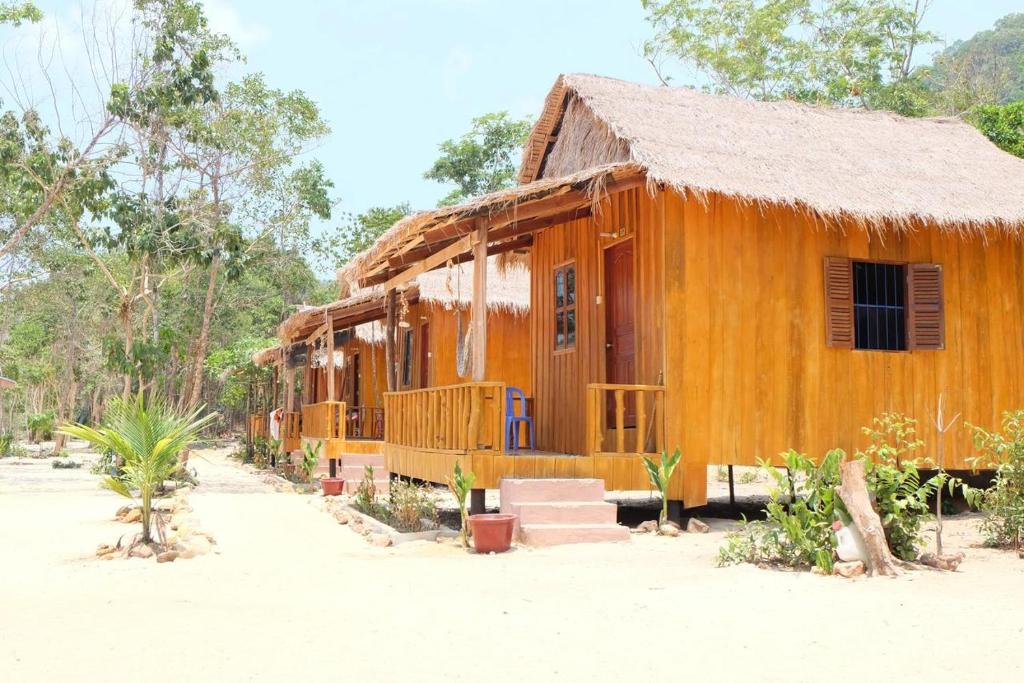 高龙撒冷岛Mangrove Beach Bungalows的前方设有门廊和楼梯的木屋