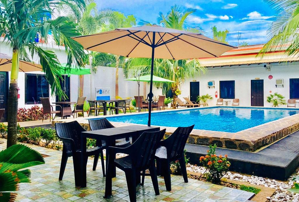 邦劳RedDoorz Plus at Palm Rise K Diving Resort Panglao Bohol的游泳池旁配有遮阳伞的桌椅