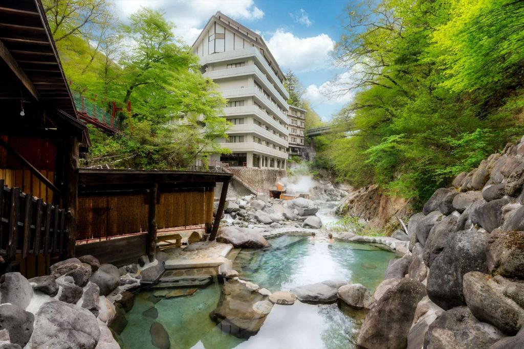 日光Nikko Nationalpark Kawamata Onsen KURA的建筑物前有岩石的河流