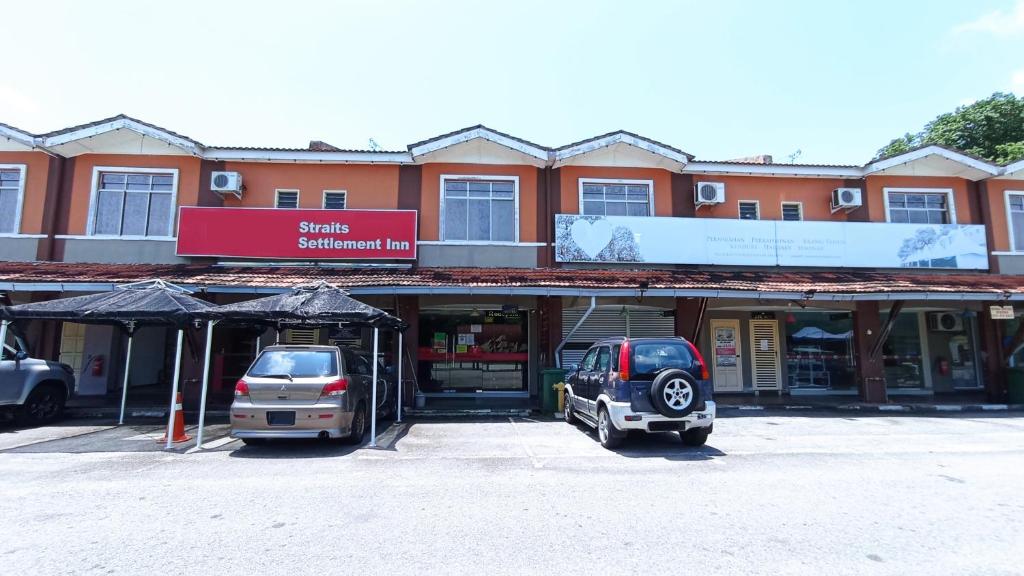 马六甲Straits Settlement Inn的两辆汽车停在大楼前的停车场