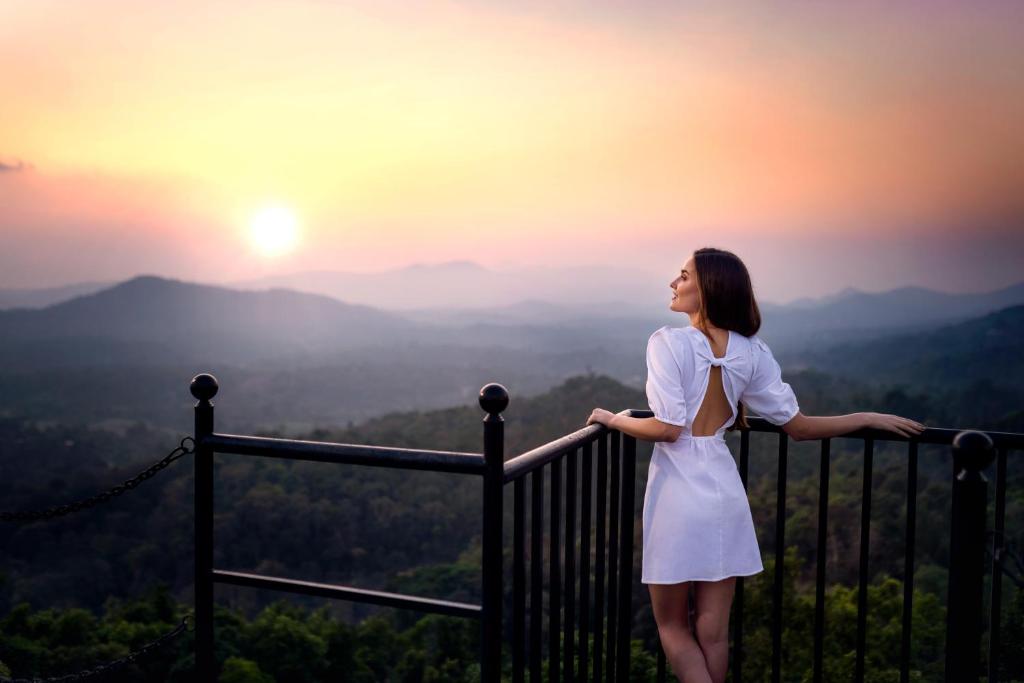 马迪凯里Coorg Wilderness Resort & Spa的站在阳台上欣赏日落的女人