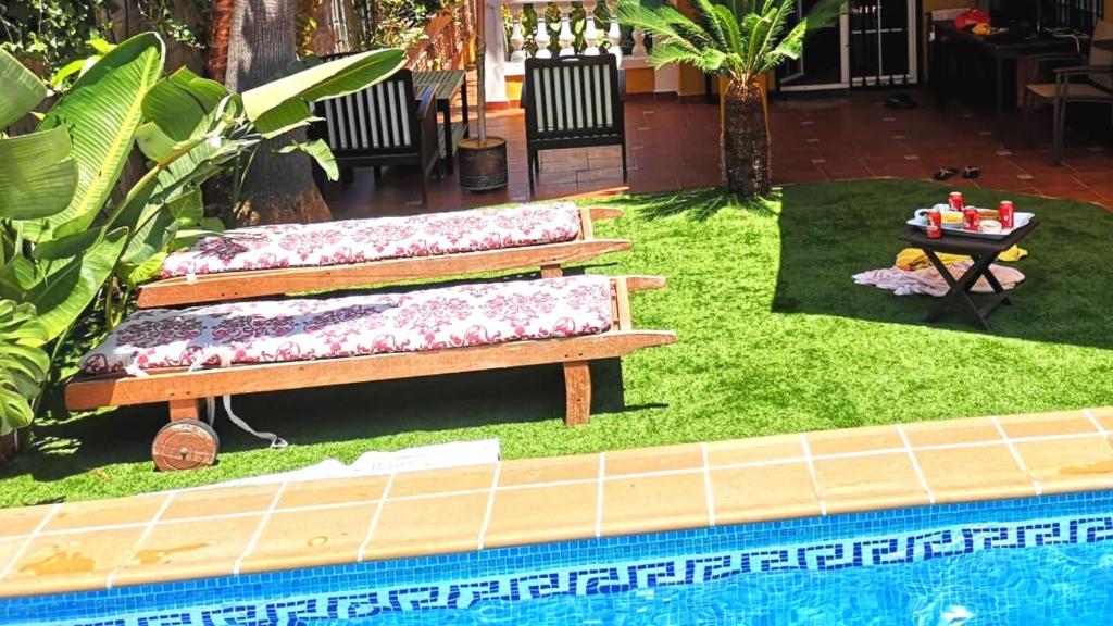 莫特里尔Villa Granada Motril的花园设有2个长椅,位于游泳池旁