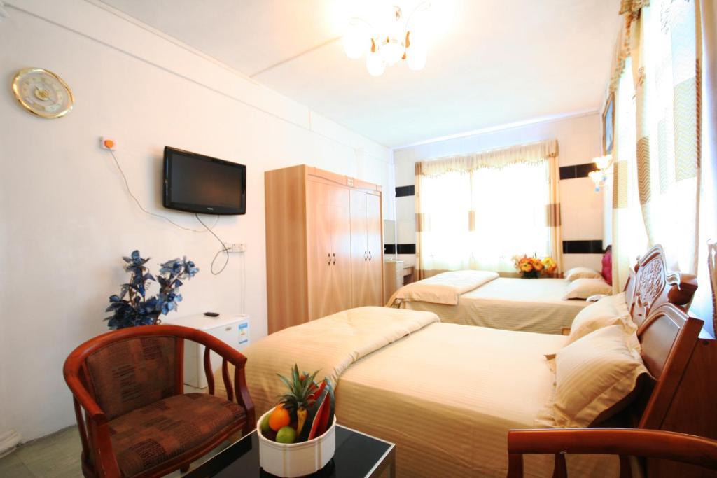 马埃堡3Ds国际旅游之家酒店的一间卧室配有两张床、一把椅子和电视。