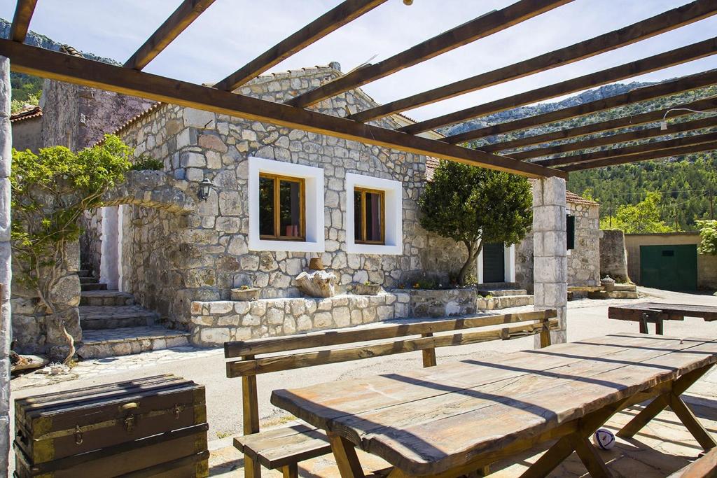 普特尼科维奇Secluded house with a parking space Tomislavovac, Peljesac - 13280的石头建筑前的木餐桌