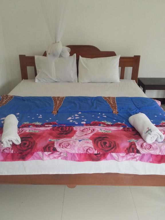 克里穆图SHILA GUEST HOUSE的一张带蓝色和粉红色毯子和玫瑰的床