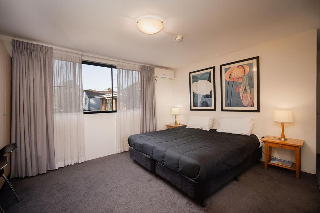 悉尼Drummoyne Furnished Apartments的一间卧室设有一张床和一个大窗户