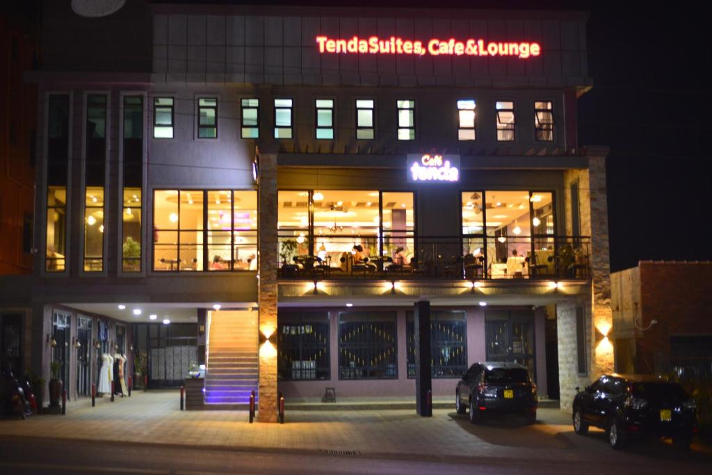 恩德培Tenda Suites and Restaurant的一座建筑,在晚上前方有标志