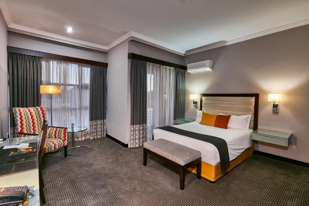 哈博罗内Regent Select Hotel的配有一张床和一把椅子的酒店客房