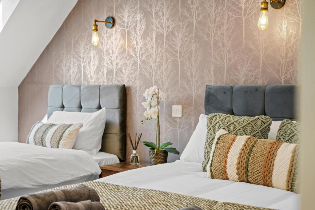 比斯特PRIME 3 BED HOUSE to BICESTER OUTLET for 8 People by Platinum Key Properties的一间卧室配有两张床,铺有粉红色的壁纸。