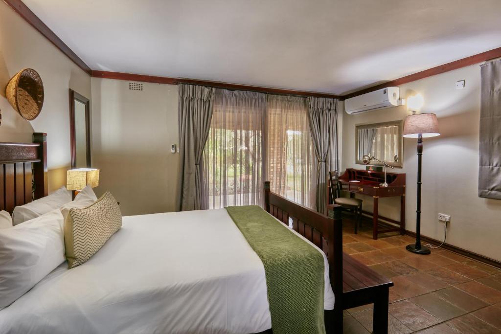 哈博罗内Manong Game Lodge的一间卧室配有一张大床和一架钢琴