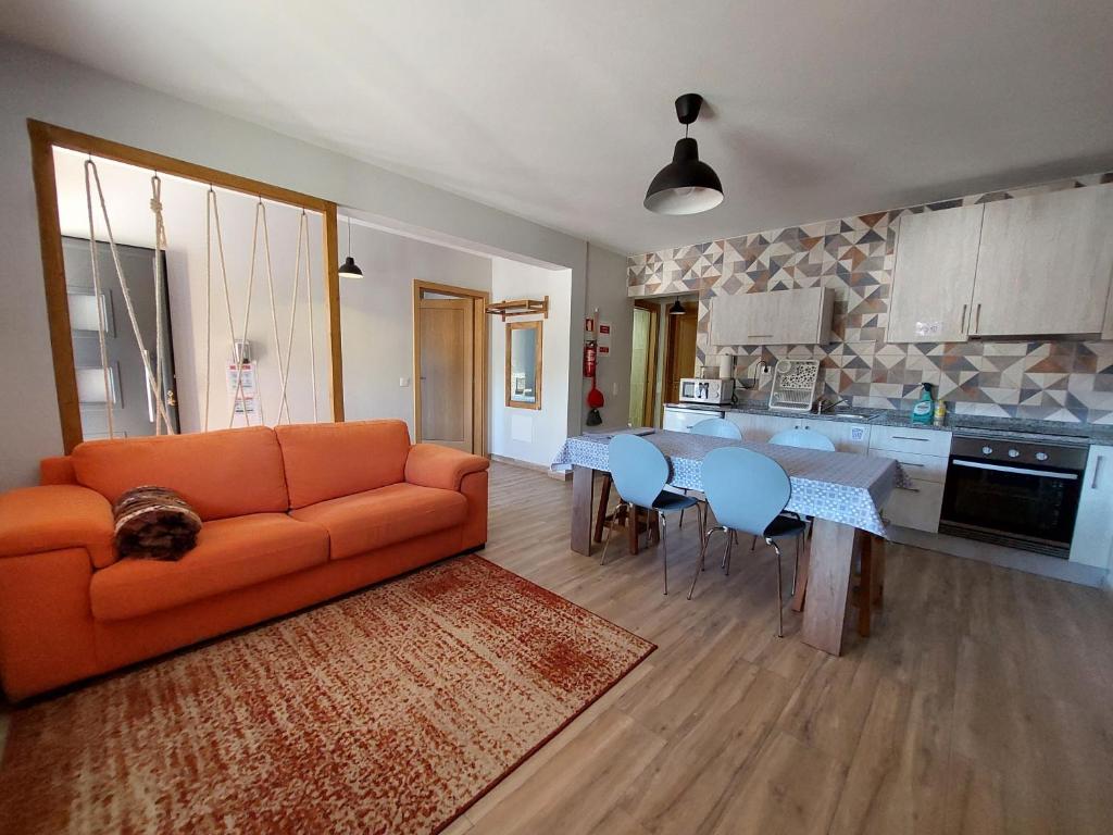 萨布盖鲁Casa do Pátio的一间带橙色沙发的客厅和一间厨房