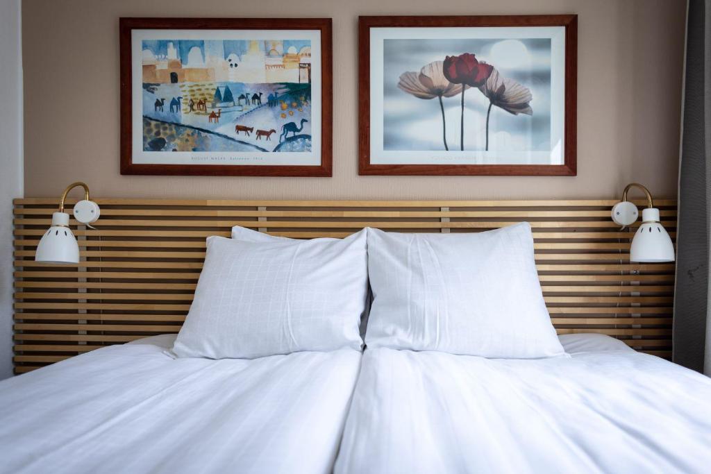 赫尔辛堡Miatorp Hotell的一张带白色枕头的床和墙上的两张照片