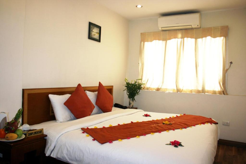 河内Hanoi Charming House的一间卧室配有带橙色枕头的床和窗户。