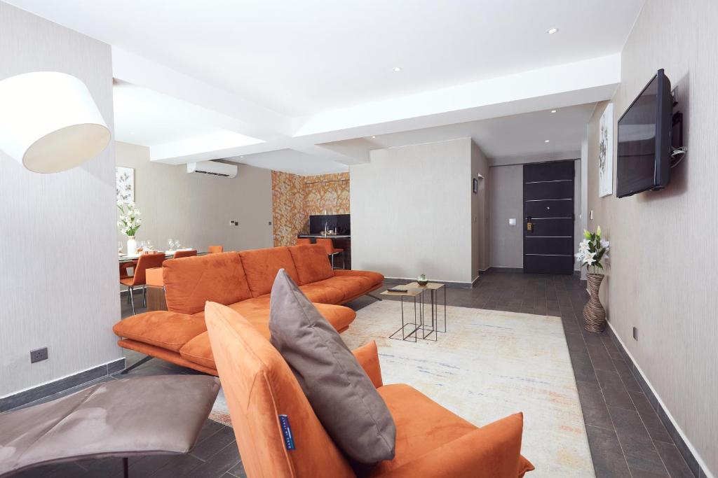 阿克拉Bel Air Crest的客厅配有橙色沙发和电视