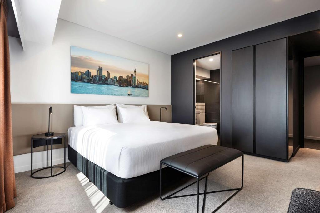 奥克兰Travelodge Hotel Auckland Wynyard Quarter的卧室配有一张白色的大床和凳子