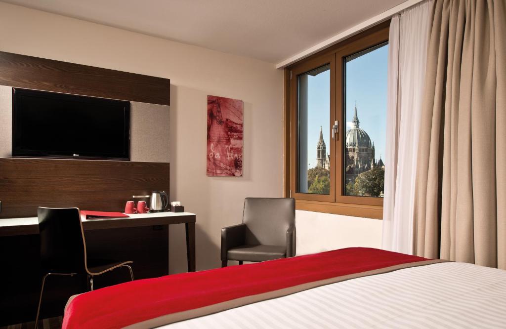 维也纳Leonardo Vienna Westbahnhof的配有一张床、一张书桌和一扇窗户的酒店客房