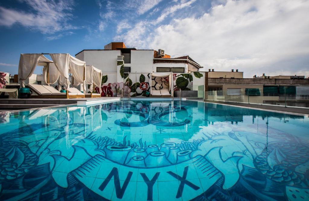 马德里NYX Hotel Madrid by Leonardo Hotels的一座建筑物边的游泳池,上面有涂鸦