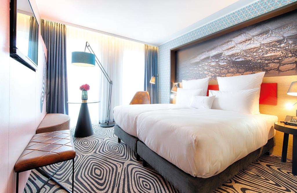 慕尼黑NYX Hotel Munich by Leonardo Hotels的酒店客房设有一张大床和一张书桌。
