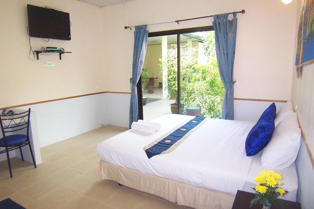 奈扬海滩普吉岛机场夜宿酒店的一间卧室设有一张床、一台电视和一个窗口。