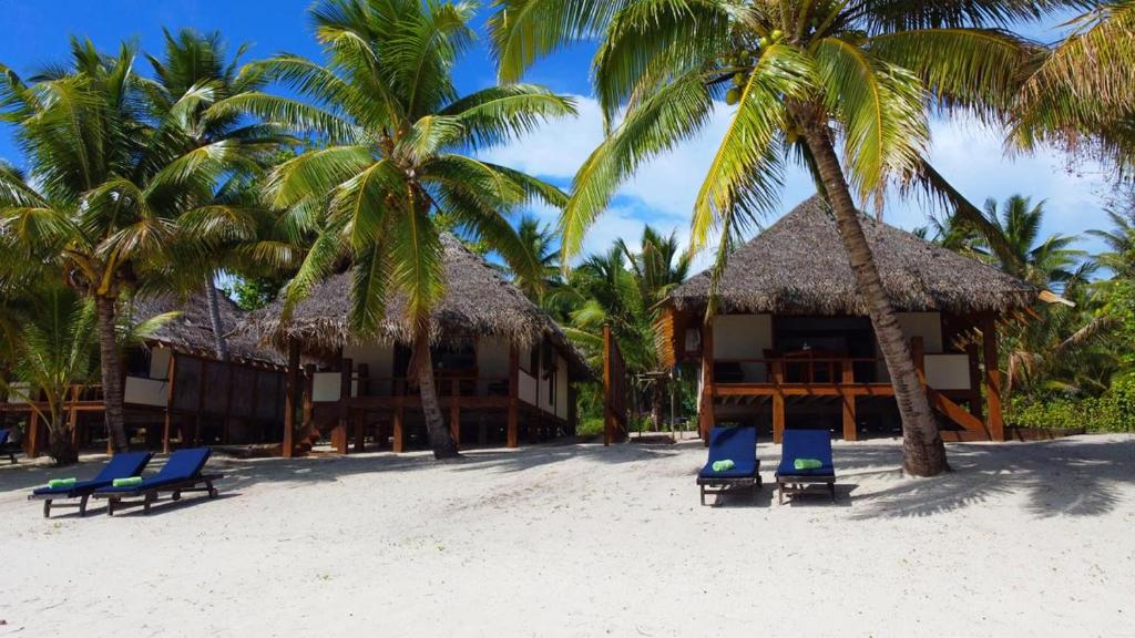 AmuriHeaven to Sea Beach Villas的海滩上的度假村,设有蓝色的椅子和棕榈树