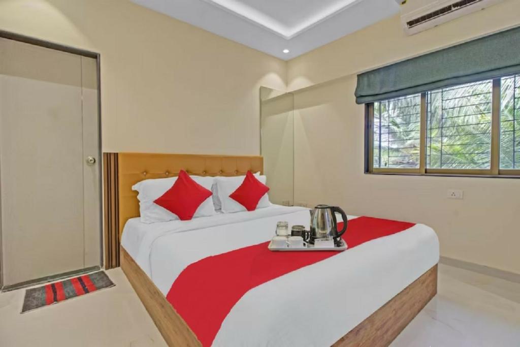 孟买Hotel Sunrise Juhu的一间卧室配有两张带红色枕头的床
