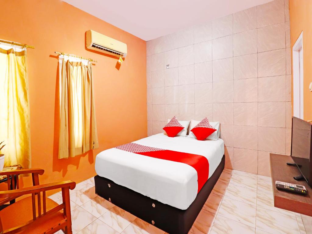 占碑市OYO 91408 Kas Residence Syariah的一间卧室配有红色和白色枕头的床